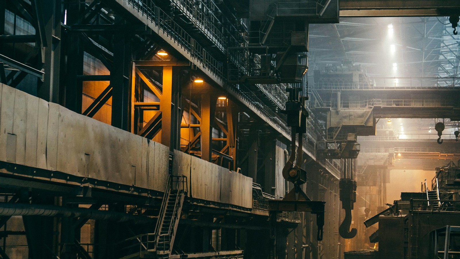 Interior of a heavy-industrial manufacturing plant with overhead cranes, metal structures and machinery