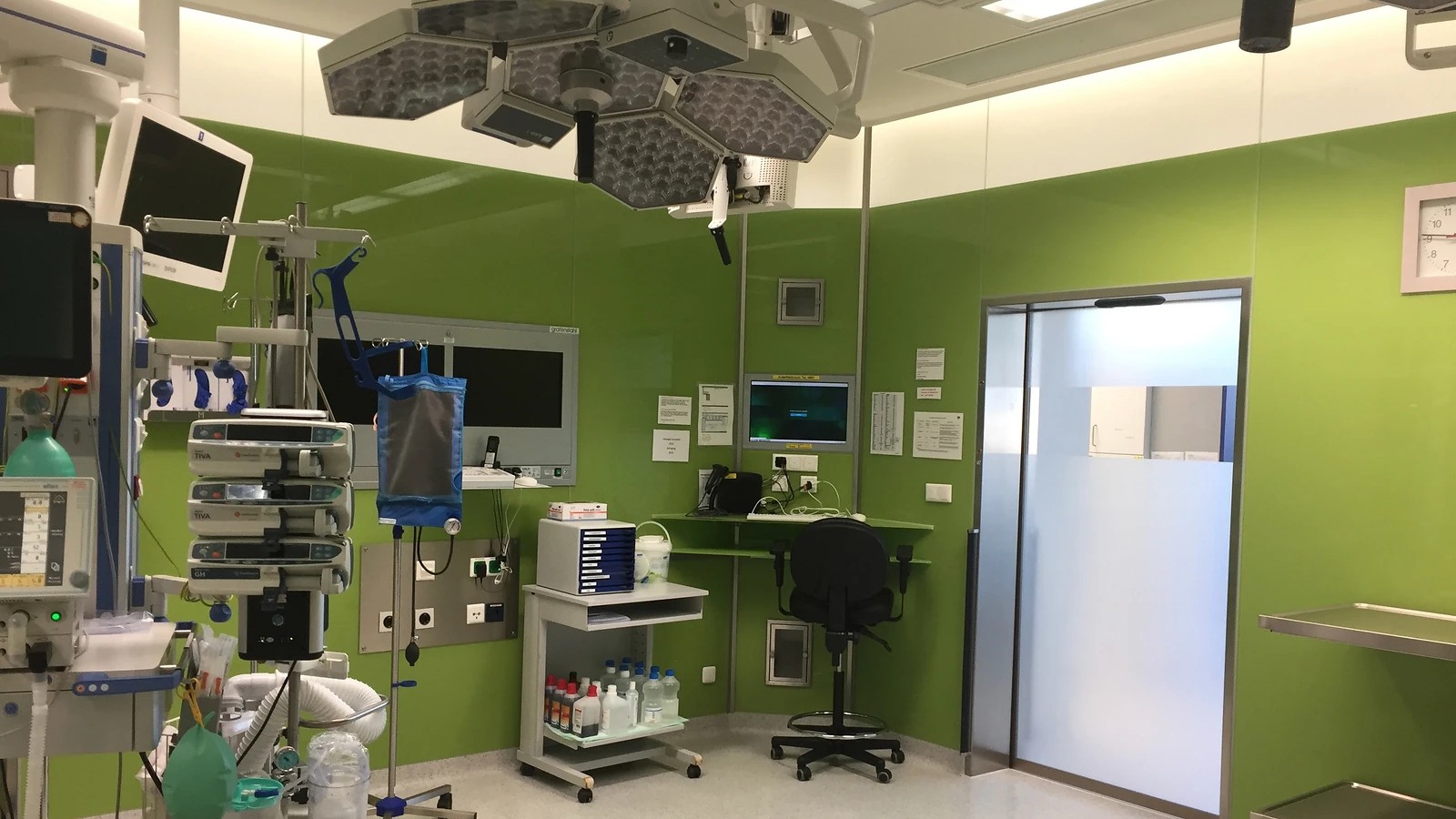 Empty operating room with surgical lights, medical equipment, clean work surfaces and a clear floor
